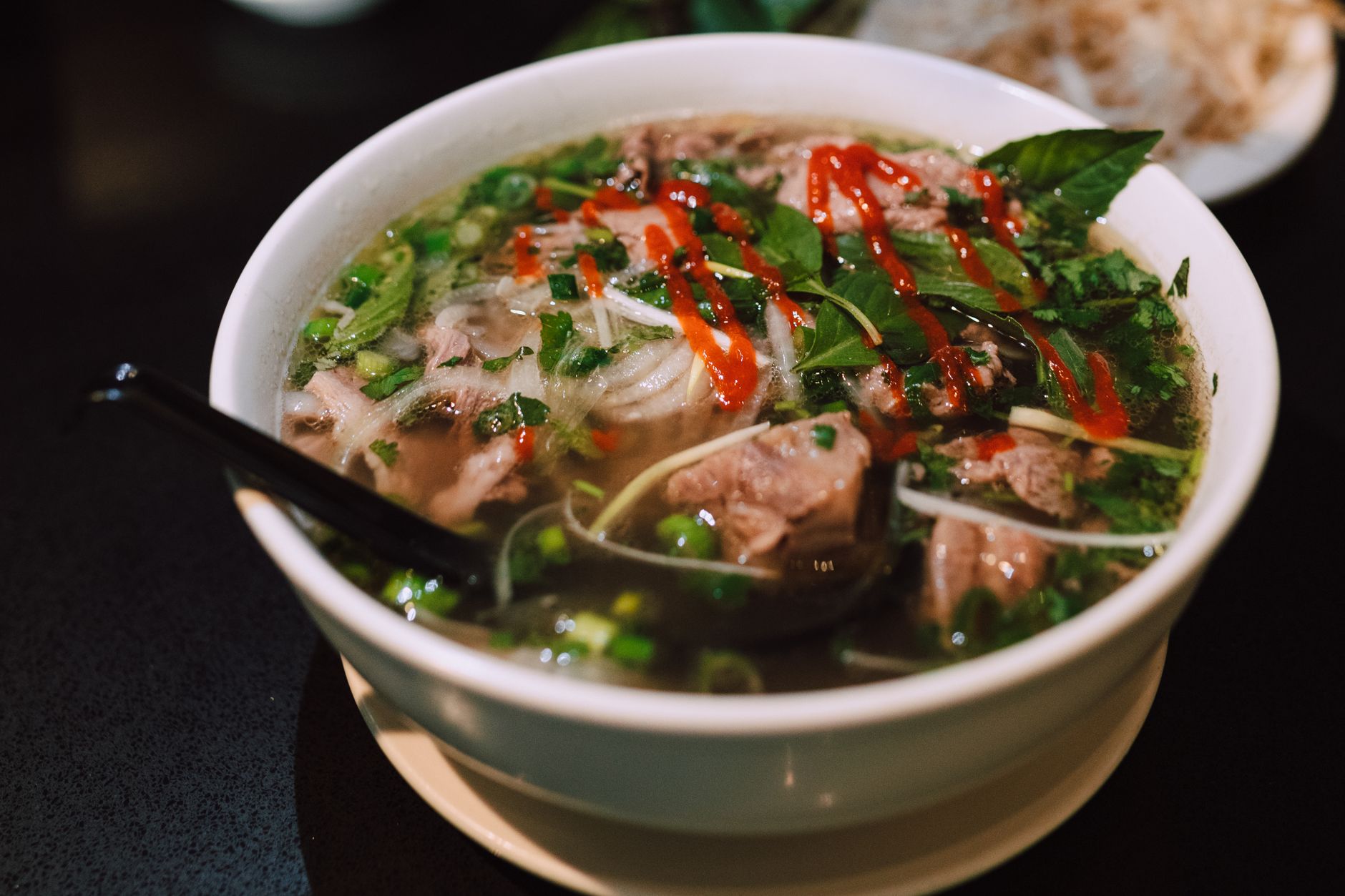Bol de pho vietnamien fumant avec herbes et nouilles de riz