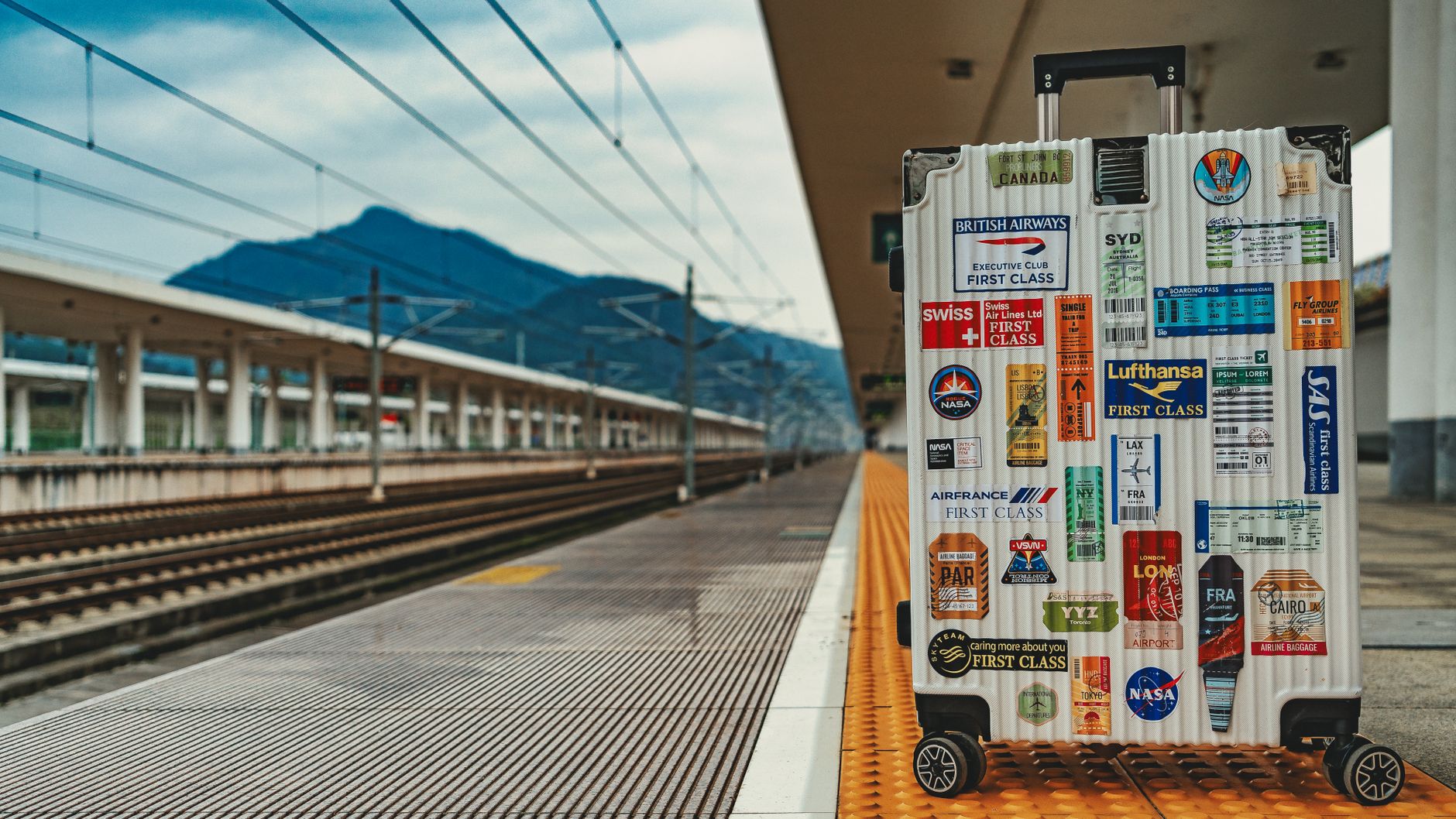 Valise couverte d'autocollants sur un quai de gare, illustration de voyage